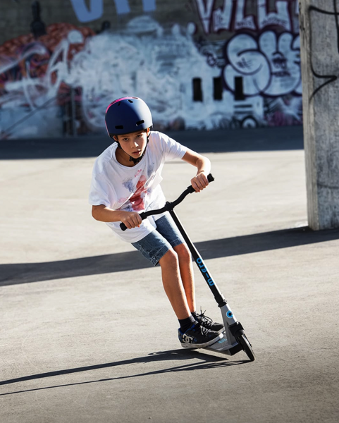 Kluk jede ve skateparku na freestyle koloběžce Micro