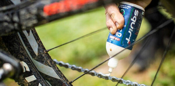 Ruka, která aplikuje mazivo na řetěz Squirt